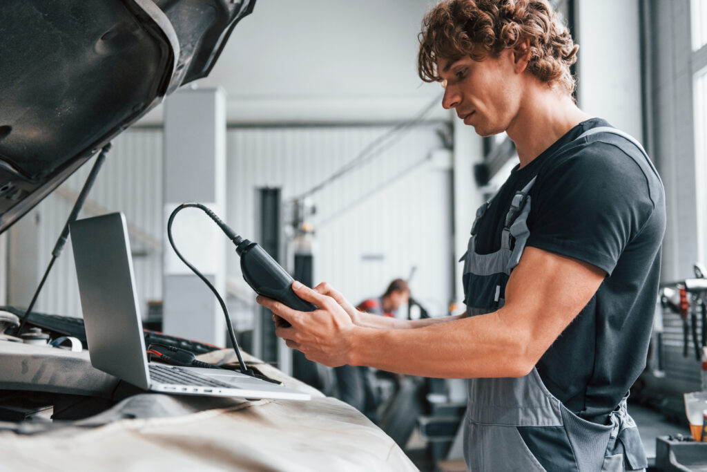 Auto mechanic using tool to understand on-board diagnostics