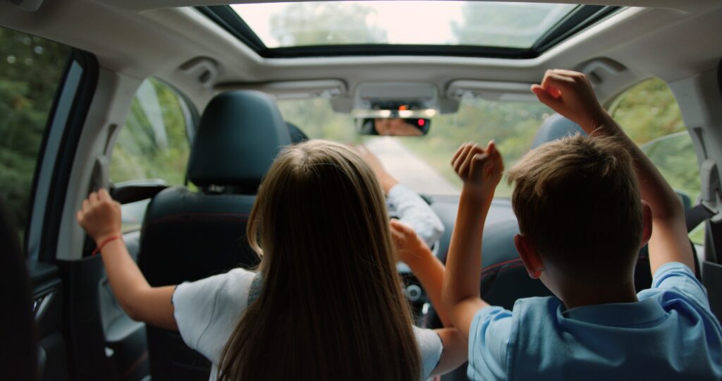 Little boy and girl listens enjoys music and dancing while road trip