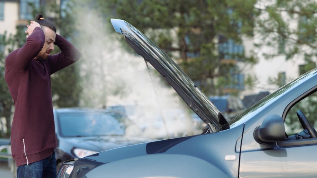 Man opens car hood and smoke goes out