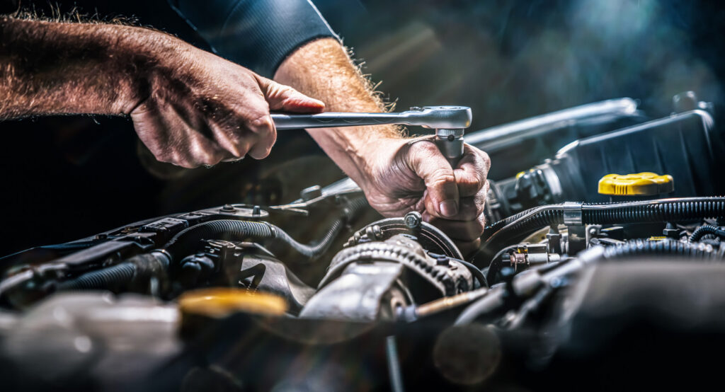 Auto mechanic working on car engine