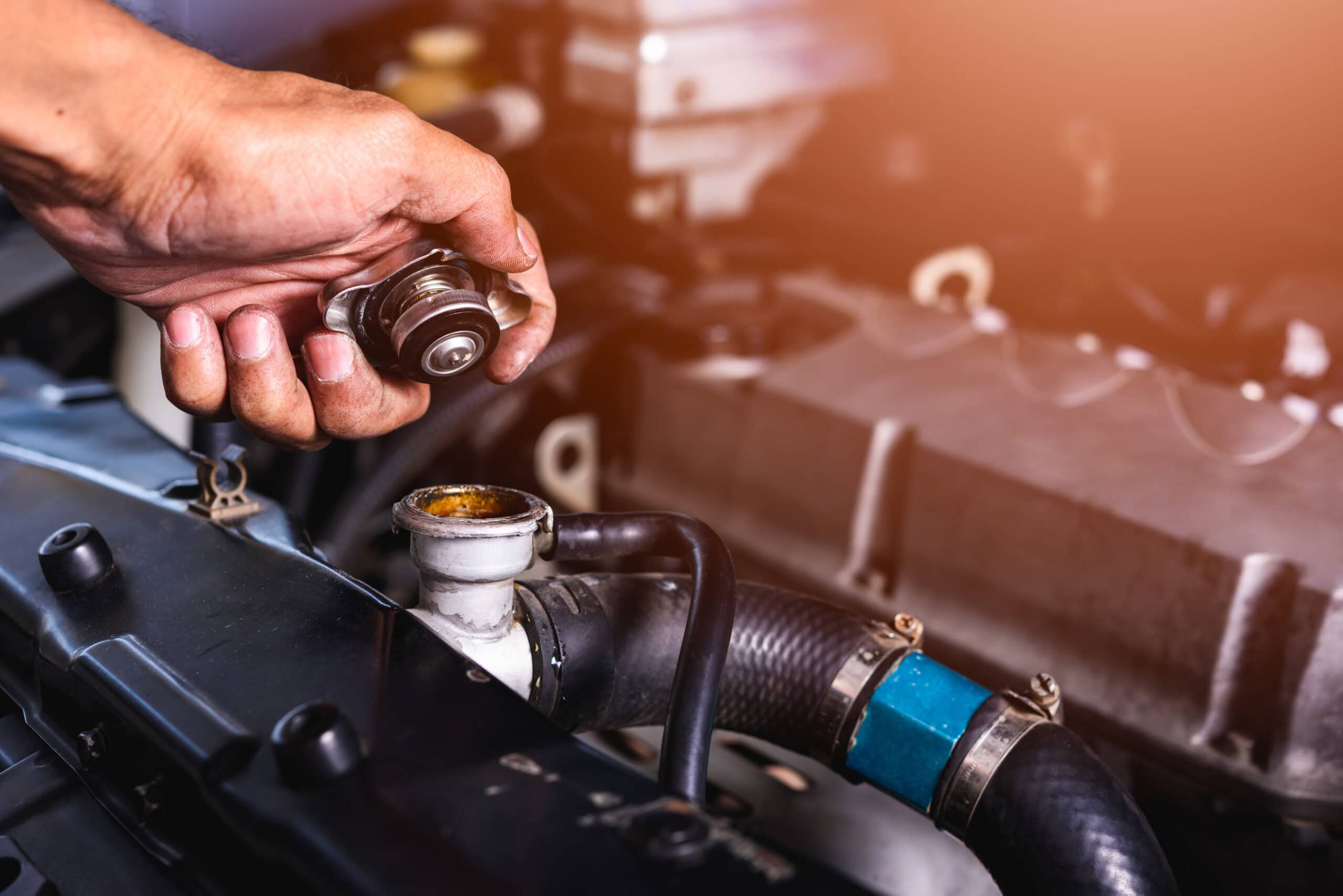 Auto mechanic checking coolant by opening radiator cap