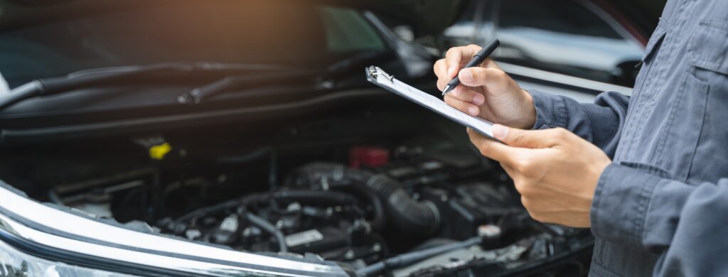 Auto mechanic writing checklist to estimate maintenance quote