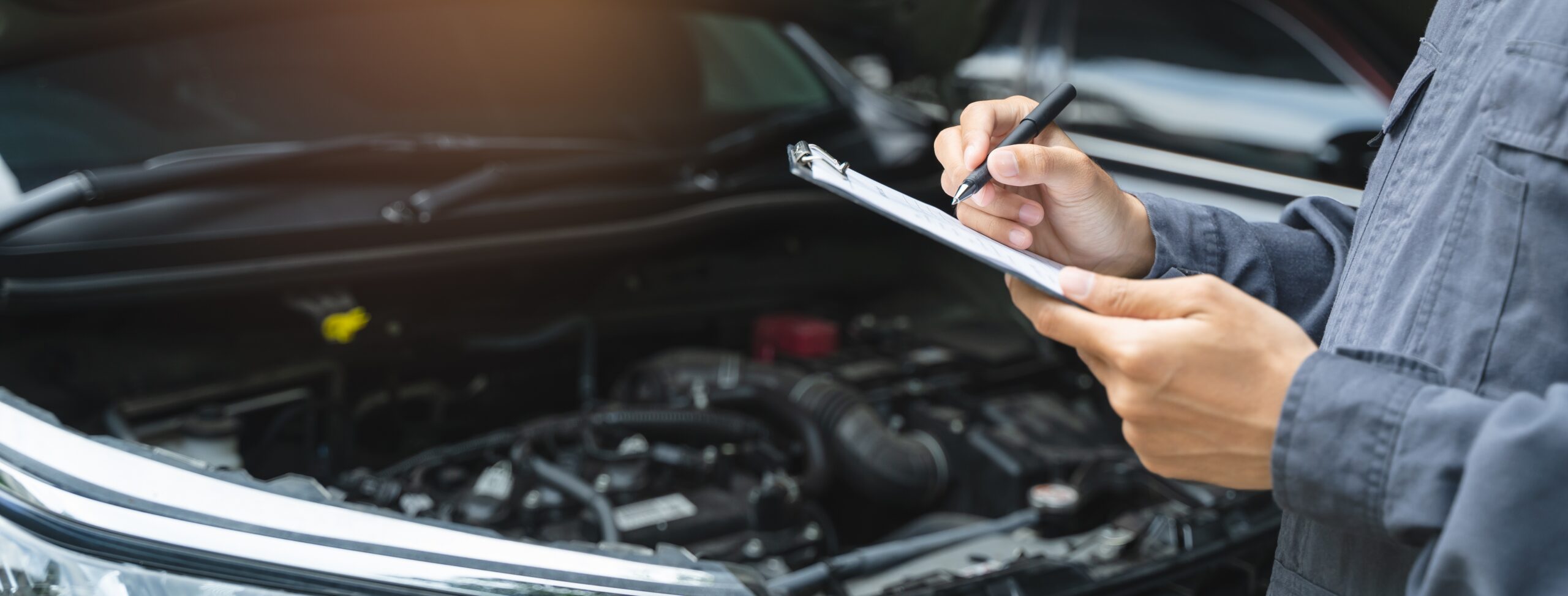 Auto mechanic writing checklist to estimate maintenance quote