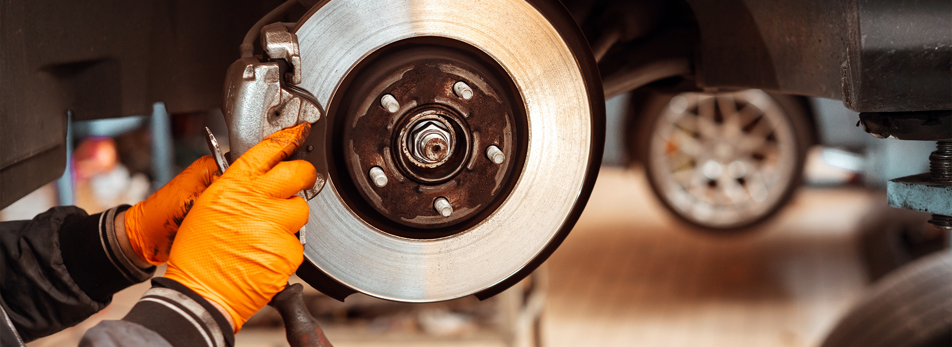 Auto mechanic replacing car wheel brake pad