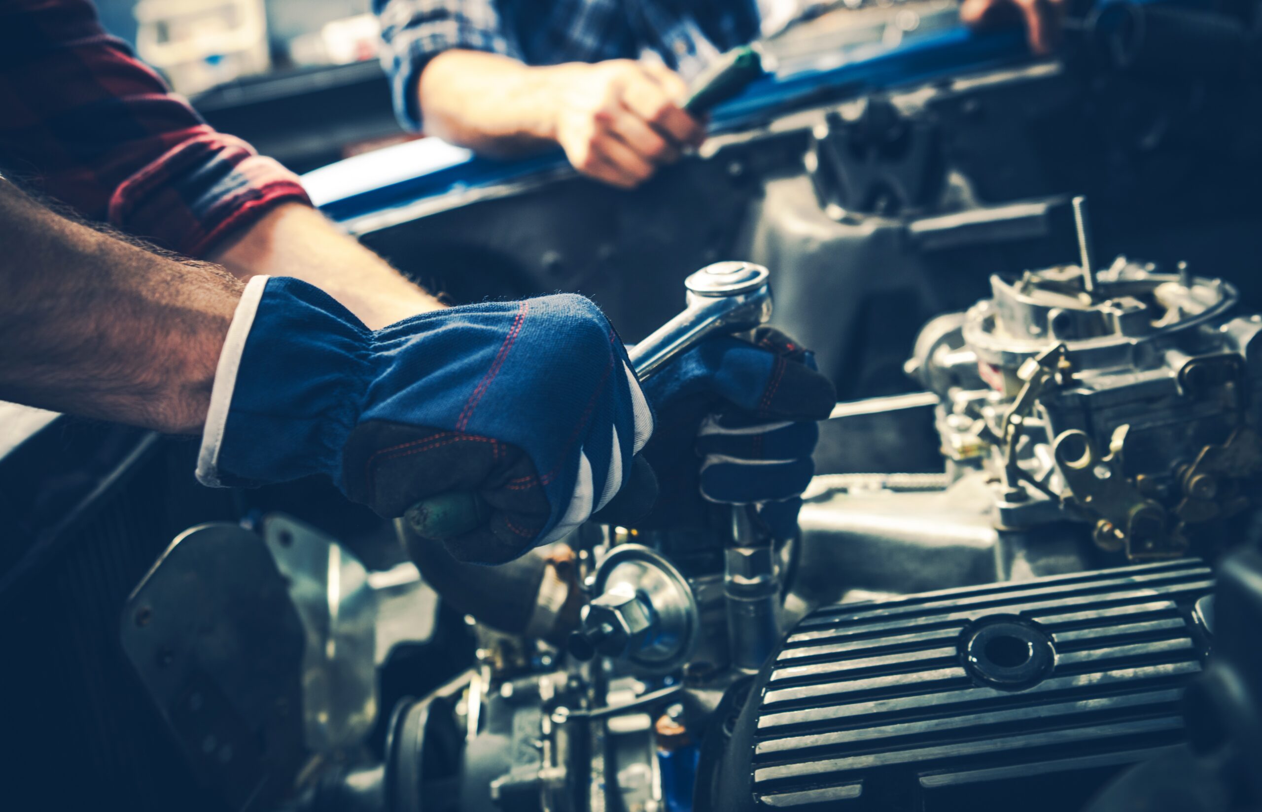 Two mechanics are focused on repairing a car engine